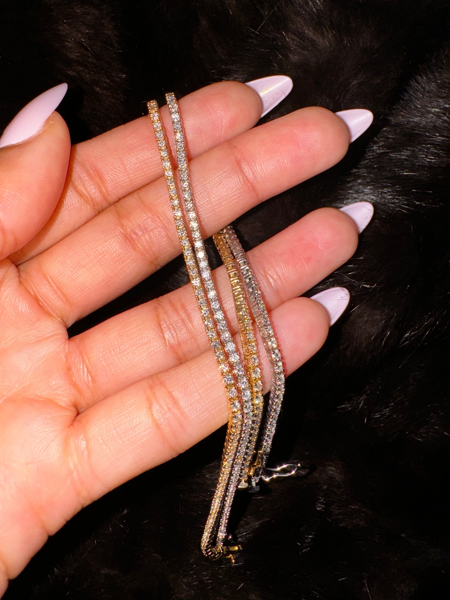 Hand is holding two diamond tennis anklets in 14K yellowgold and whitegold