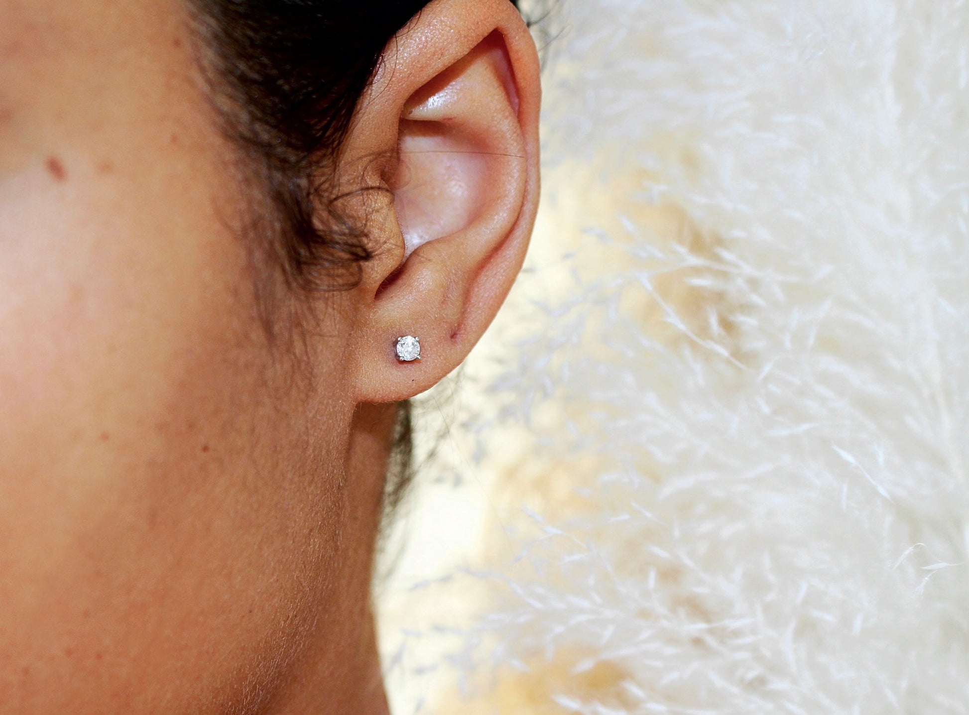 single diamond stud earring on left of of model