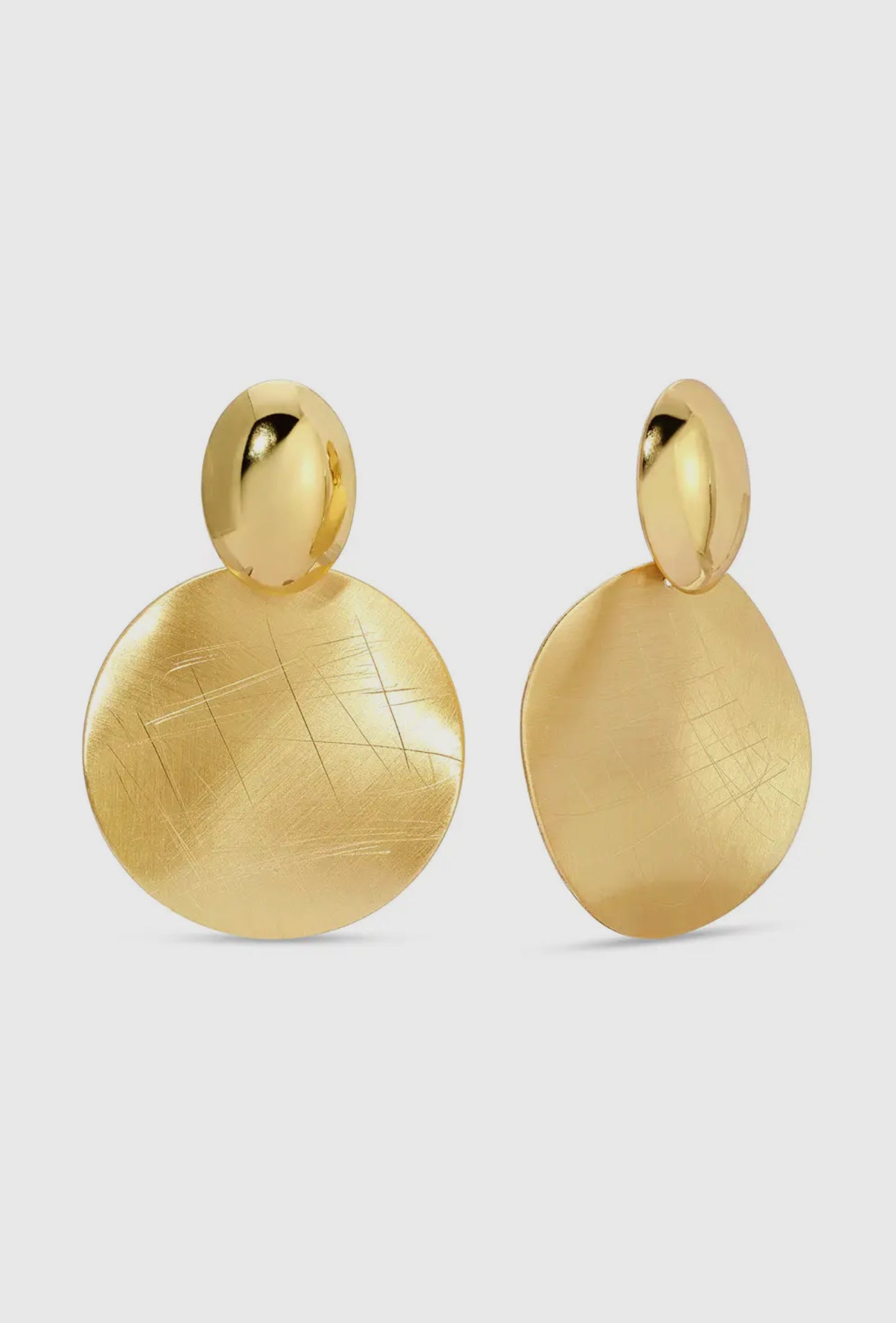 Gold earrings on a light gray background